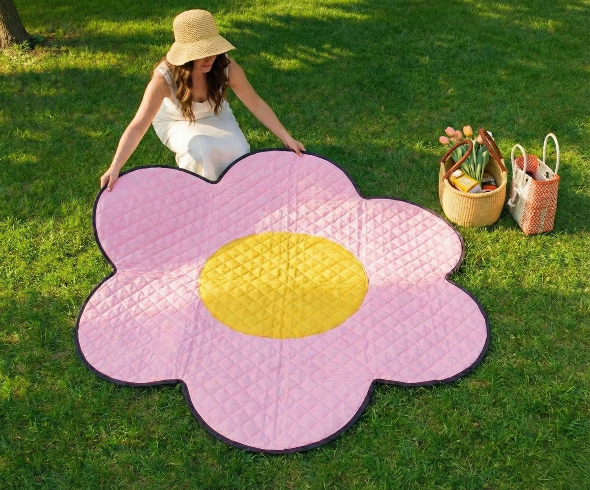 Femme assise sur la couverture de pique-nique Flower Power en forme de fleur dans un parc